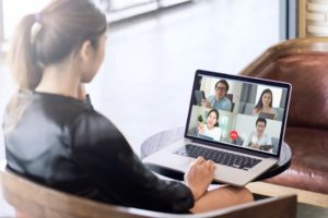Back view of business woman talking to her team in a video conference.